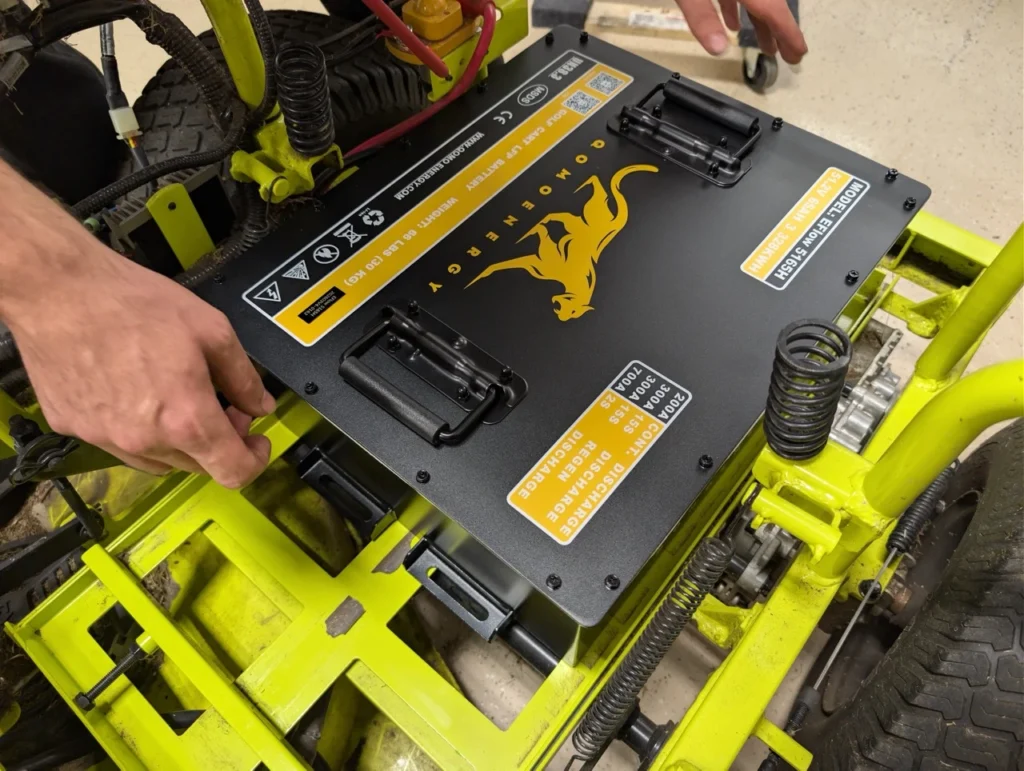 The Qomolander 48V 65Ah battery kit perfectly replaces the factory lead acid batteries, but does require disassembly of the mowers seat to properly reach.